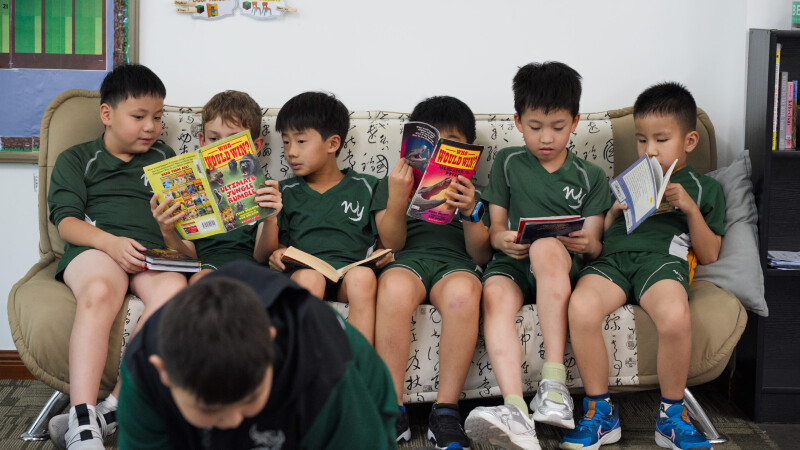 A group of elementary students reading books together on a couch in class at Wuhan Yangtze International School.