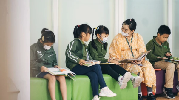 wuhan yangtze international school teacher reading a book to young students