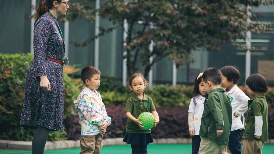 wuhan yangtze international school teacher playing a ball game with young male and female students
